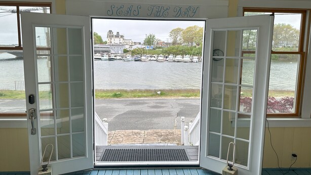 A room with a view of a harbor, a door with glass panels, and a sign above the door that reads "SEA THE DAY". - Waterfront Home with Game Room, Kayaks, near beach (Wareham)