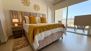 Een moderne slaapkamer met een groot bed, een nachtkastje, een lamp en uitzicht op de omgeving door een schuifdeur.