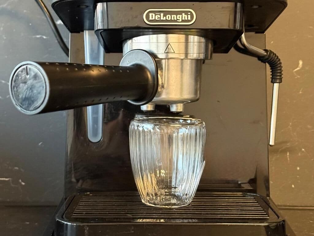 A Delonghi espresso machine with a clear glass carafe.