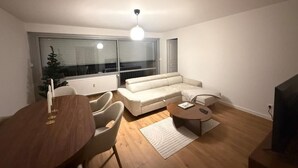 A modern living room with a sofa, a dining table, and a TV. - Superb 3-bedroom apartment in the heart of Mulhouse (Mulhouse)