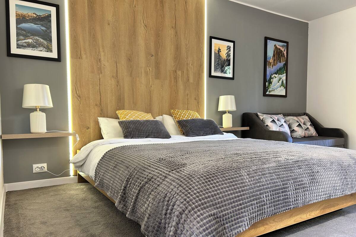 A modern bedroom with a large bed, two bedside tables, and a wooden headboard.