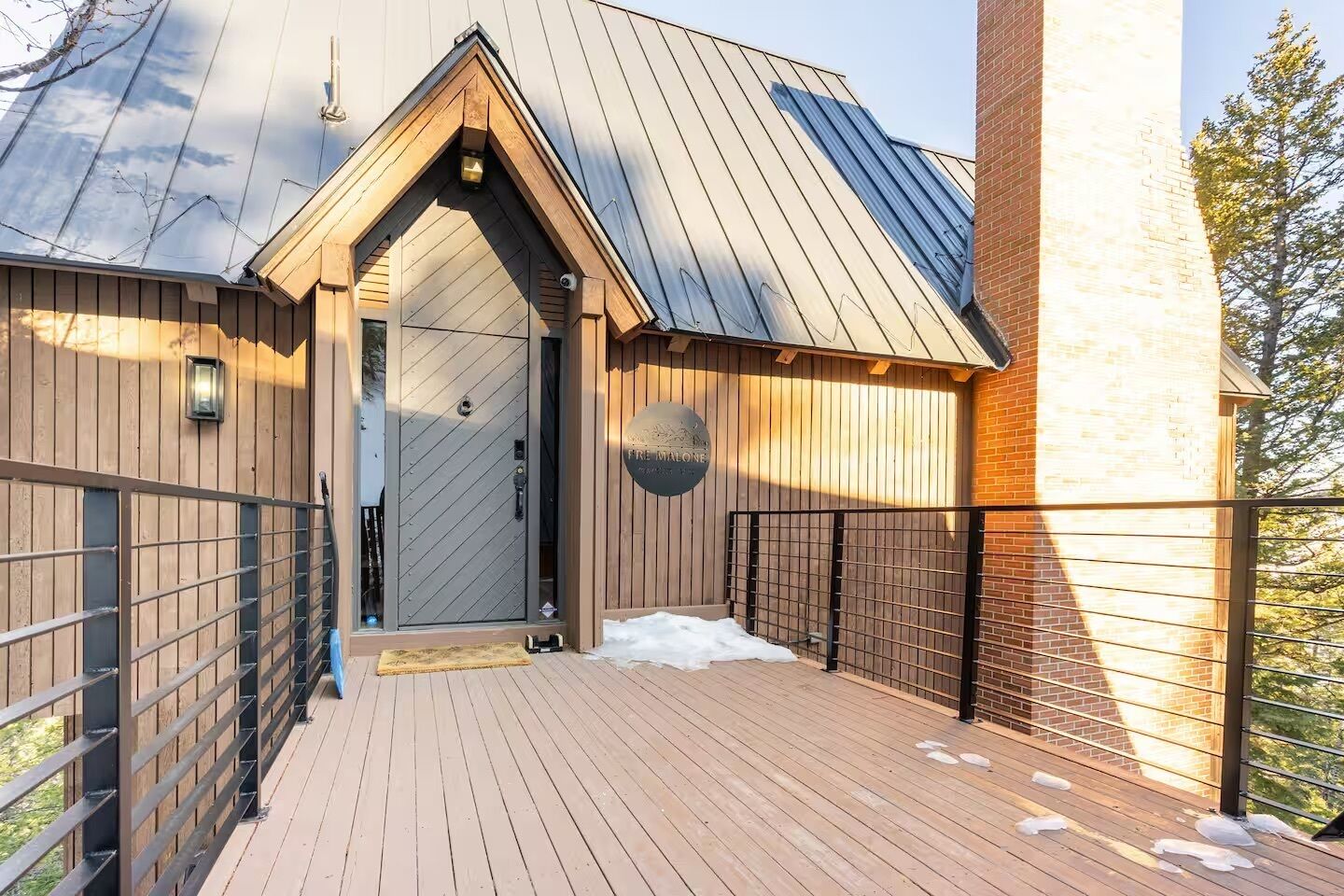 A modern building with a metal roof, wooden exterior, and a gated entrance.