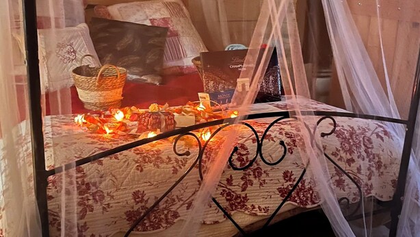 Ein Bett mit Baldachin, ein Nachttisch und ein Korb.