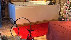 Ein Zimmer mit Steinwand, einer großzügigen Badewanne, einer Holzbalkendecke und einem roten Teppich.