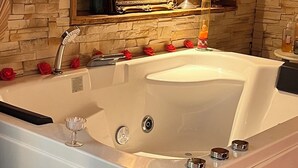 Ein Badezimmer mit einer großen Badewanne, einem Spiegel über dem Waschbecken und einer Steinwand.