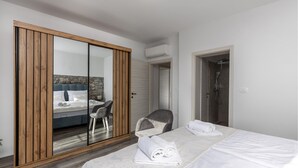 Ein Hotelzimmer mit Bett, Stuhl, Kleiderschrank, Badezimmer und Klimaanlage.