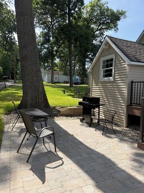 A patio area with a grill, chairs, and a small shed with the number 1610.