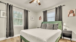 A bedroom with a large bed, a nightstand, a ceiling fan, and a window with curtains. - The Tanglewood lower suite (Chattanooga)