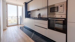 Una cocina moderna con un ventanal grande, un microondas, horno y un juego de cuchillos sobre la encimera.