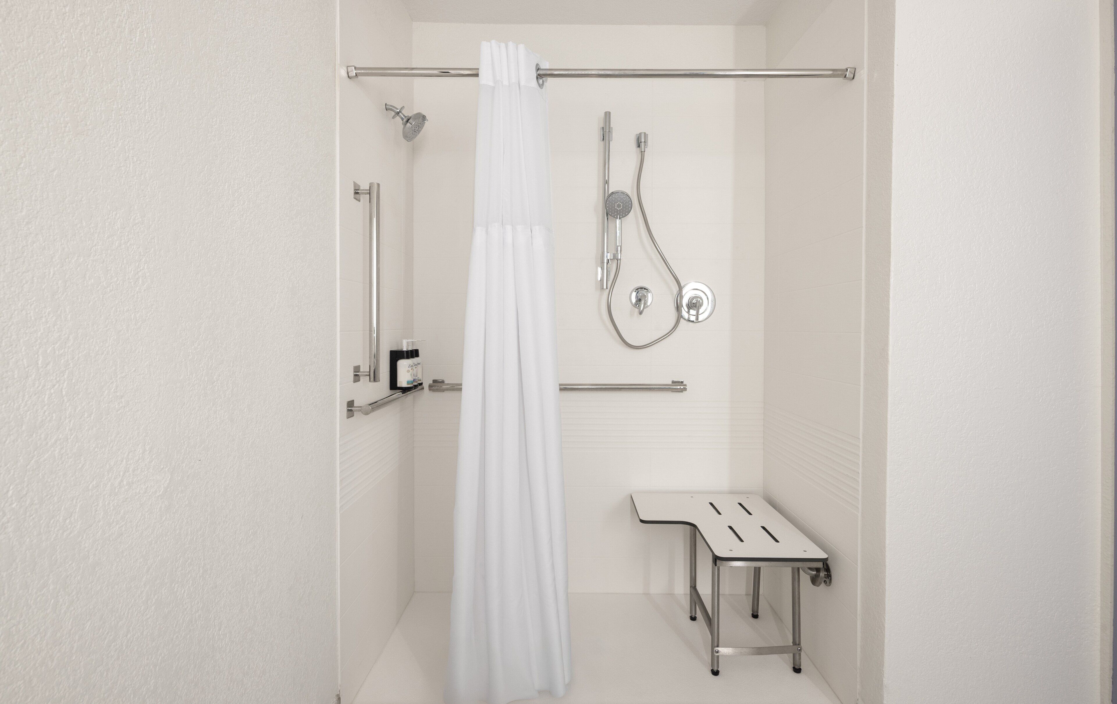 A modern bathroom with a shower, a toilet, and a small table.