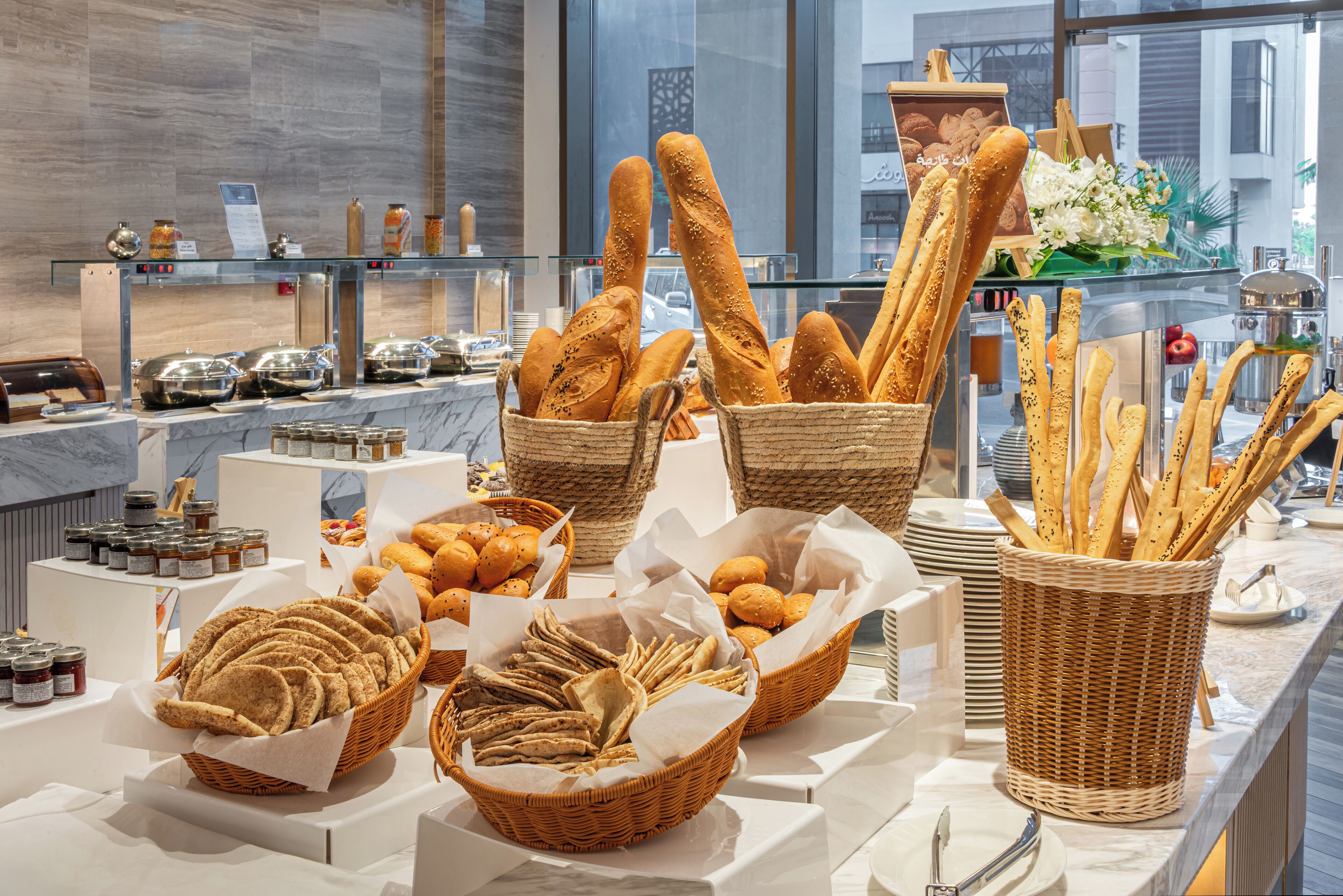 A buffet with various breads and pastries displayed in baskets and on a counter.