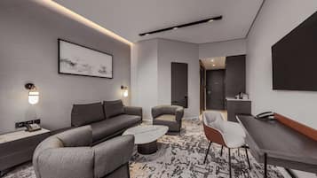 A modern hotel room with a sofa, armchair, coffee table, and a desk with a telephone.