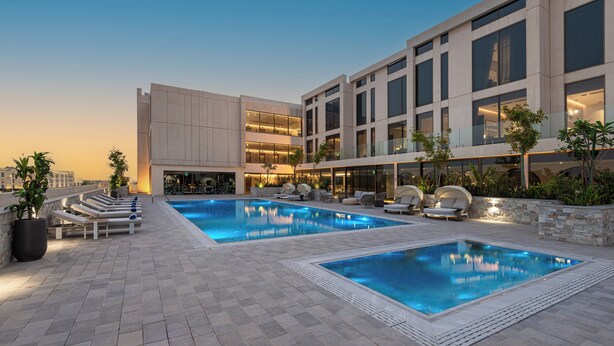 Ein modernes Hotel mit zwei Schwimmbecken, Liegestühlen und einem gut beleuchteten Außenbereich.