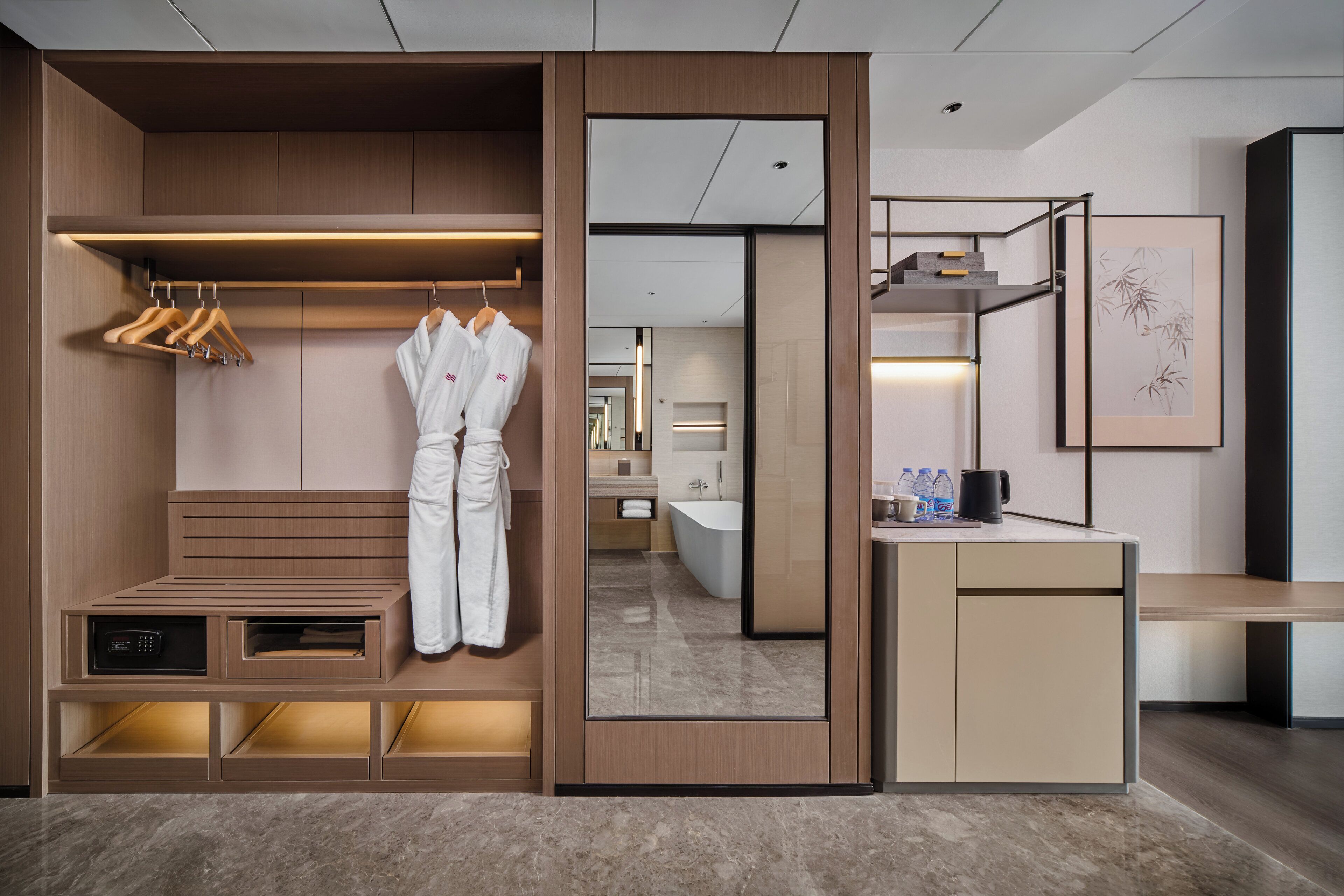Una habitación de hotel moderna con vestidor, tocador y un pequeño escritorio con espejo.