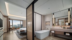 Una habitación de hotel moderna con una cama grande, un escritorio y un baño con bañera y tocador.