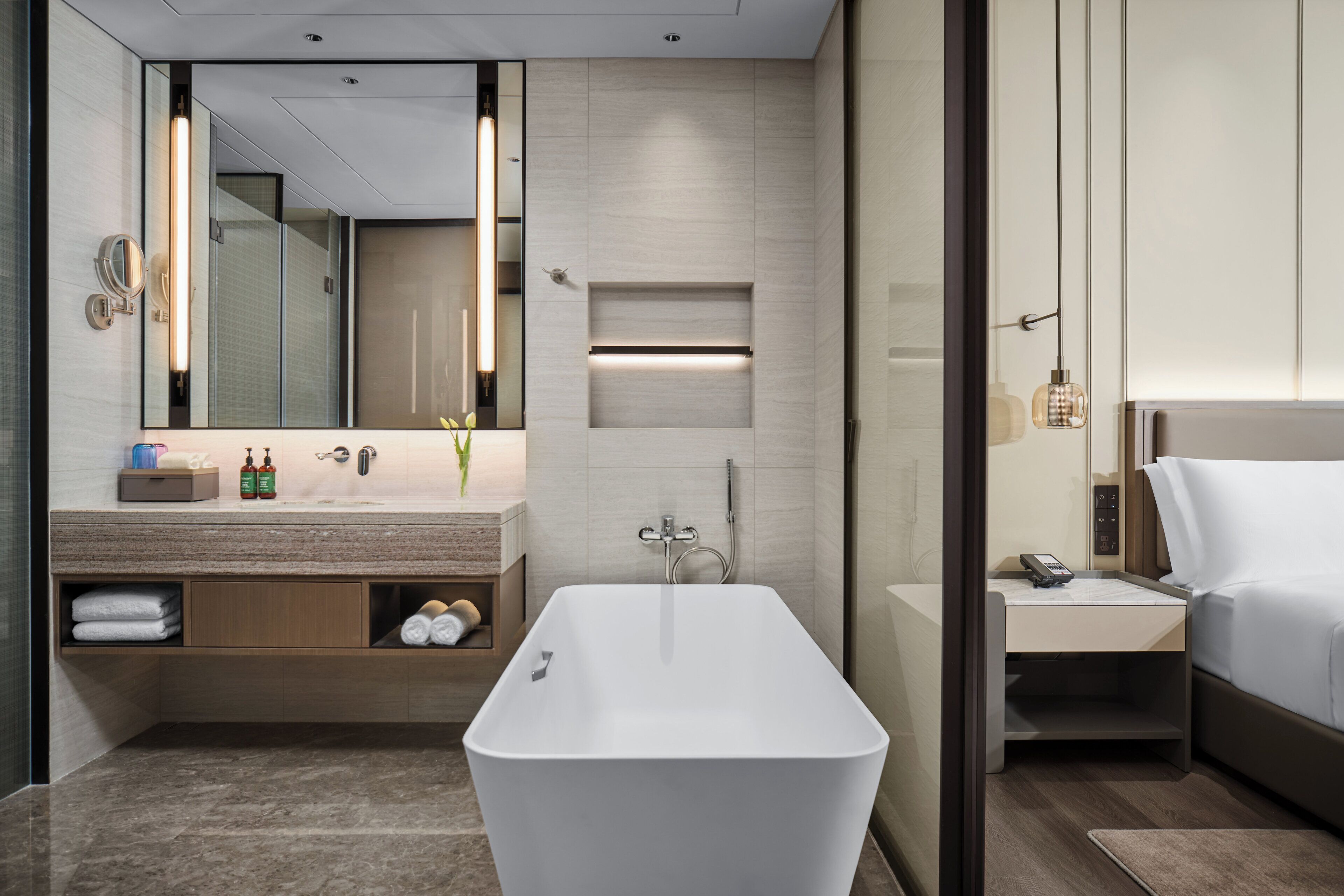 Un bagno moderno con una vasca da bagno freestanding, un mobile toilette con uno specchio e un comodino con un telefono.