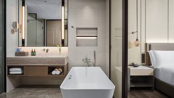 Un bagno moderno con una vasca da bagno freestanding, un mobile toilette con uno specchio e un comodino con un telefono.