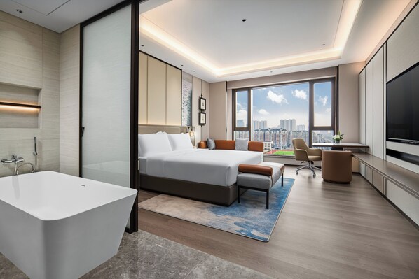 A modern hotel room with a large bed, a sitting area, a desk, a TV, and a city view. - Crowne Plaza Xinghua By Ihg (Taizhou)