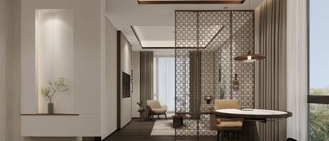 A modern hotel room with a wooden floor, a dining area with a round table and chairs, a large window with a view, and a decorative partition with a geometric pattern.