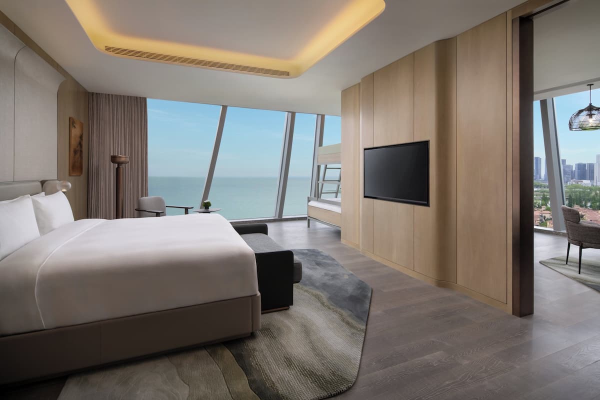Ein modernes Hotelzimmer mit einem großen Bett, einem Fernseher und Blick auf die Stadt.