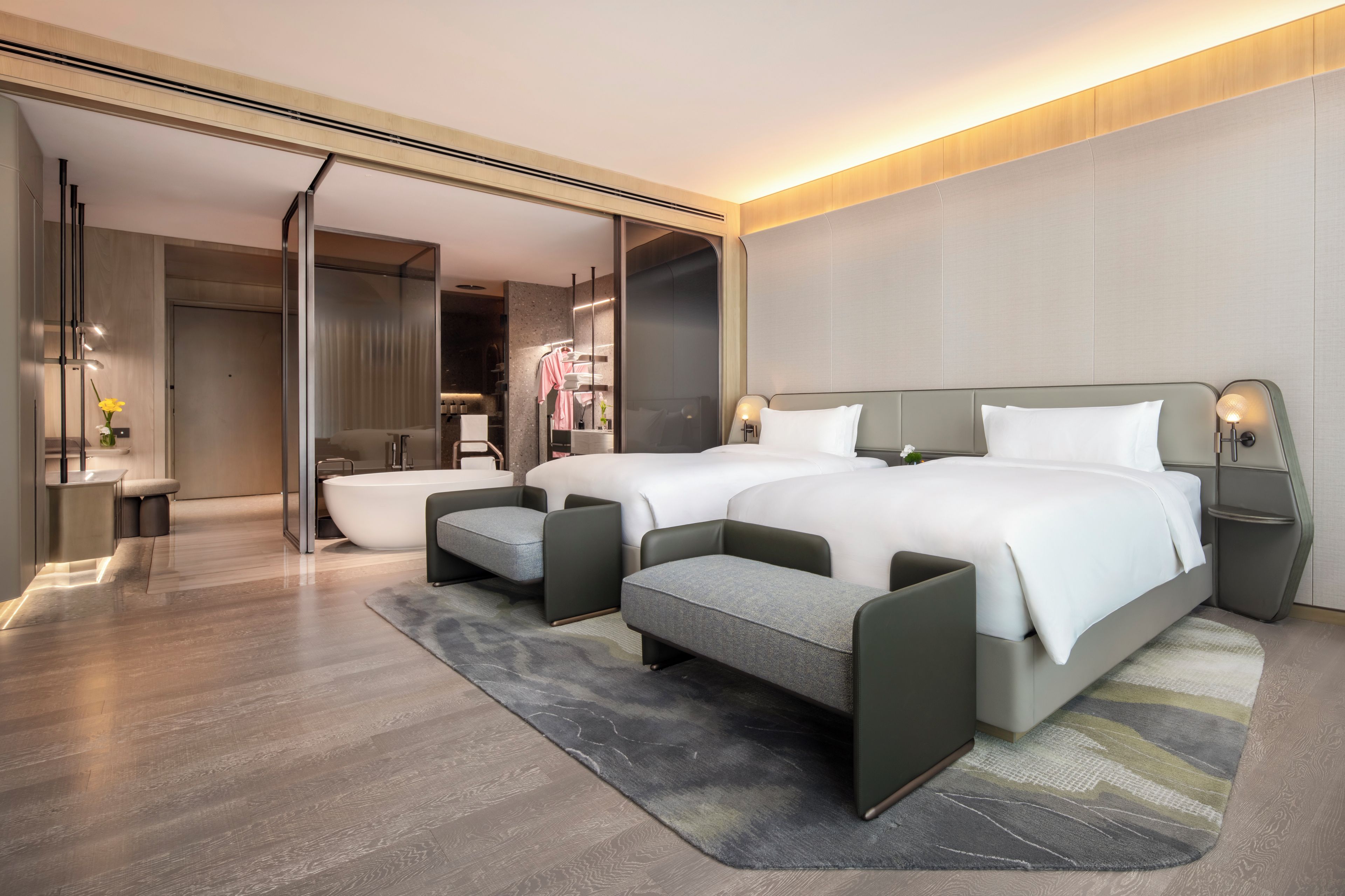 Une chambre d’hôtel moderne avec deux lits, un coin salon et une salle de bain.