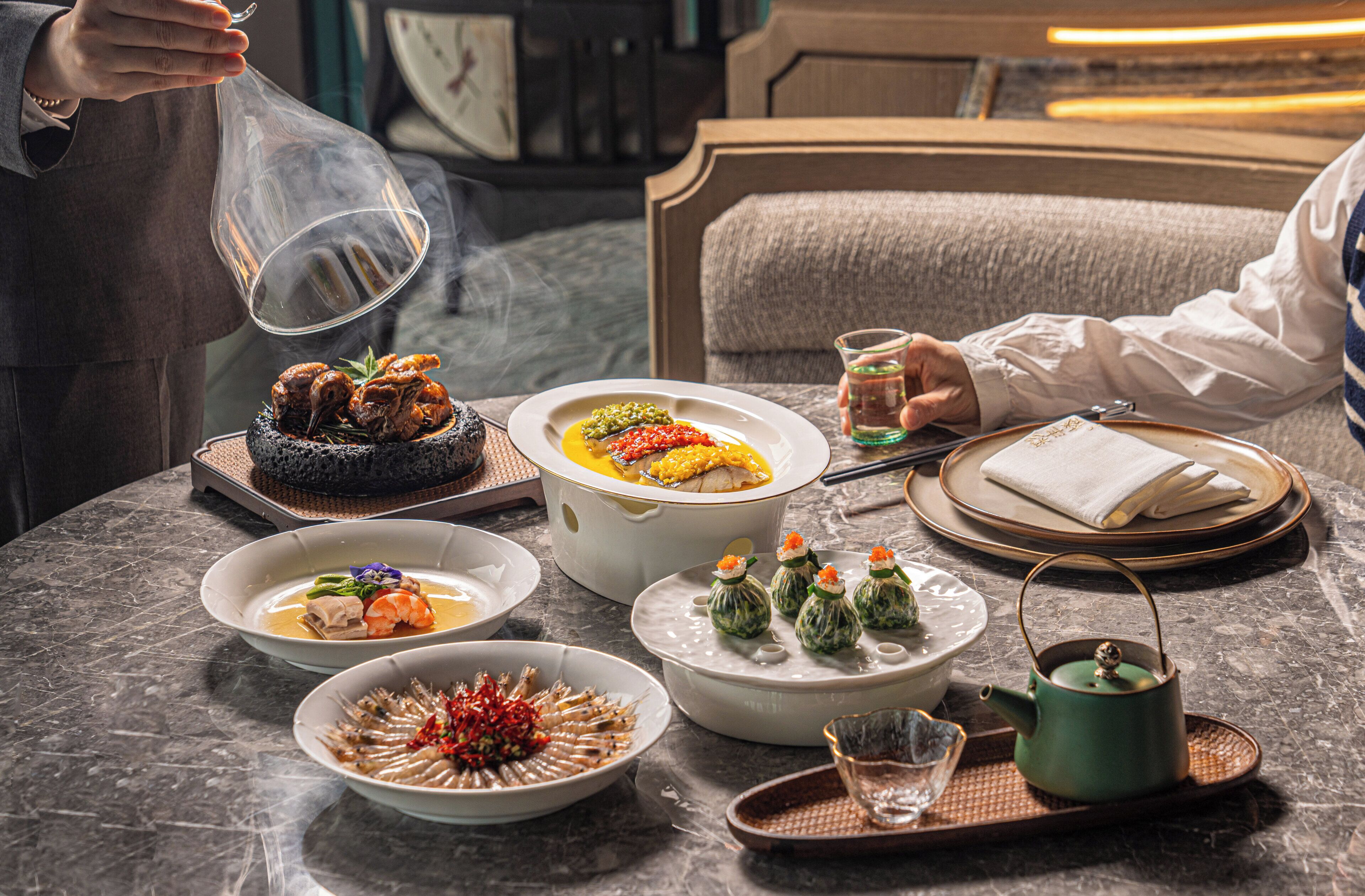 A table set with various dishes, a teapot, and a glass of water.