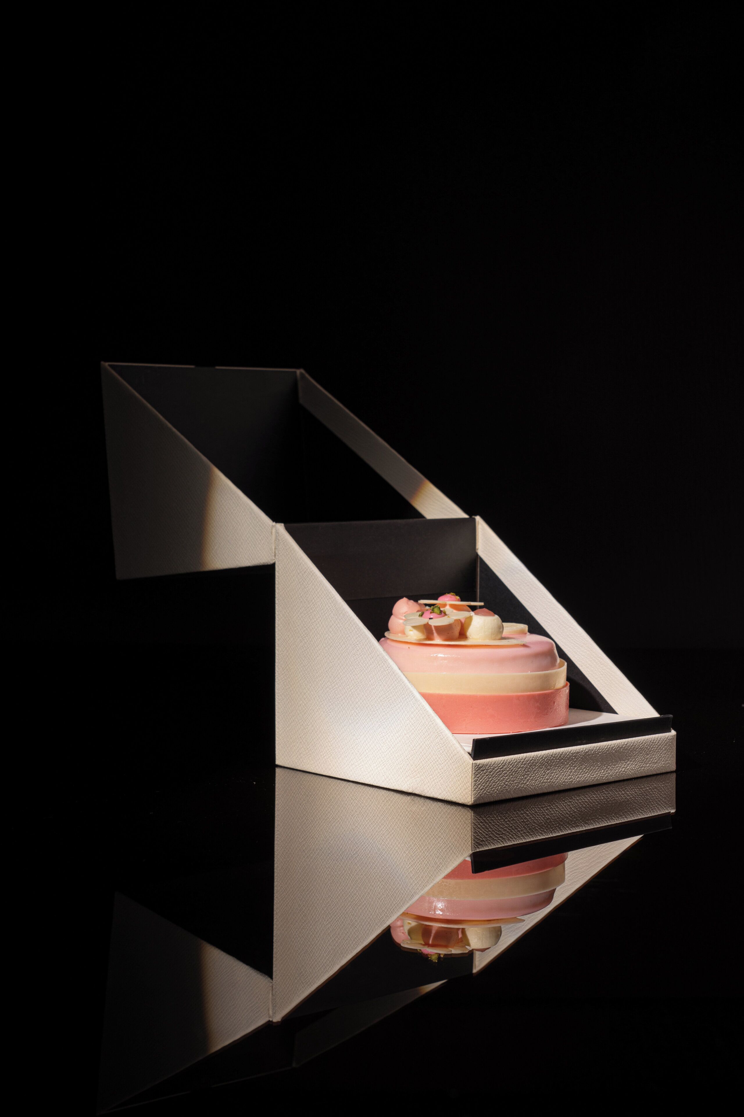 A dessert in a geometric display case with reflective surfaces.