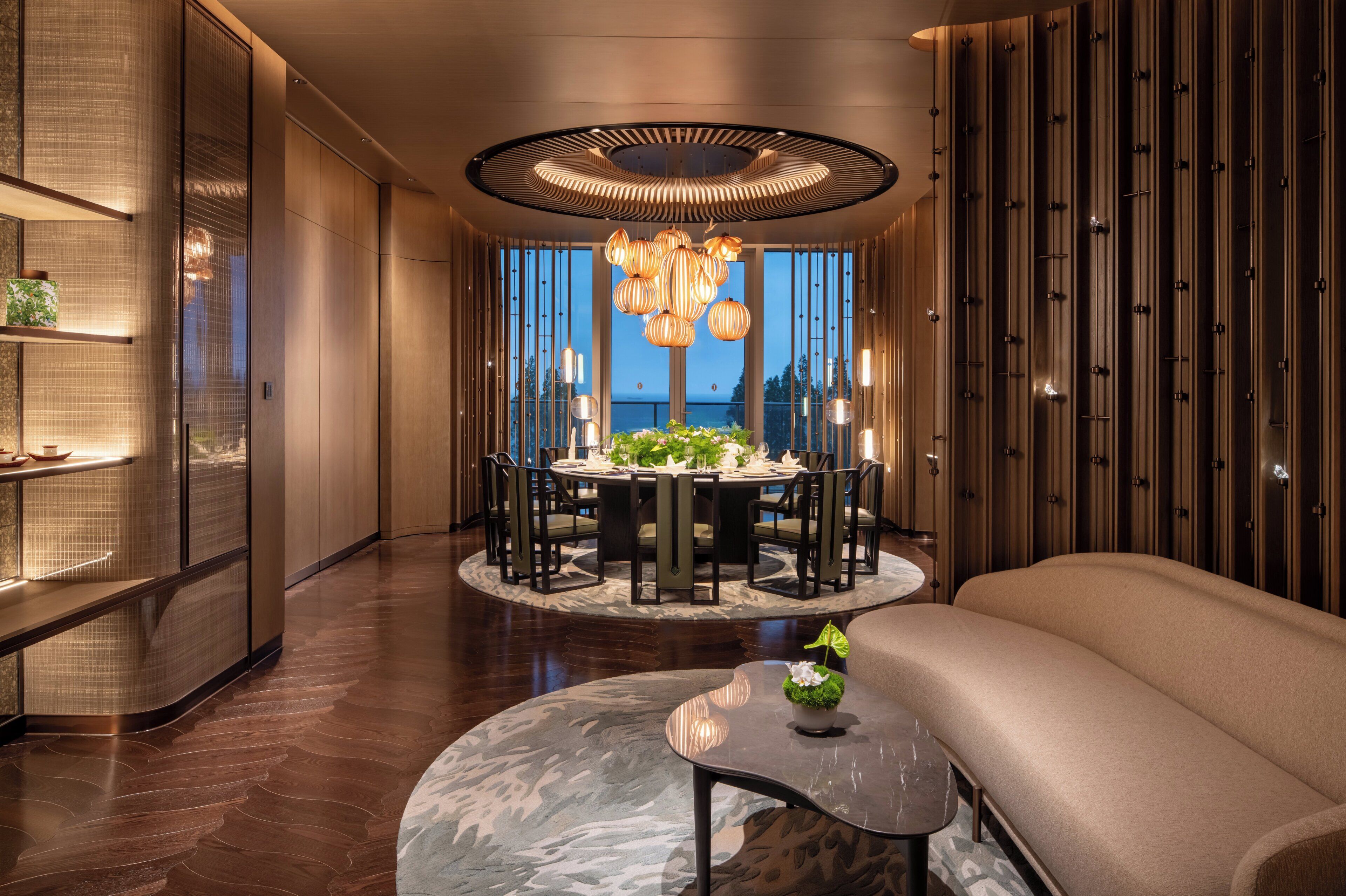 A modern interior with a round dining table, chairs, a sofa, and a unique ceiling light fixture.