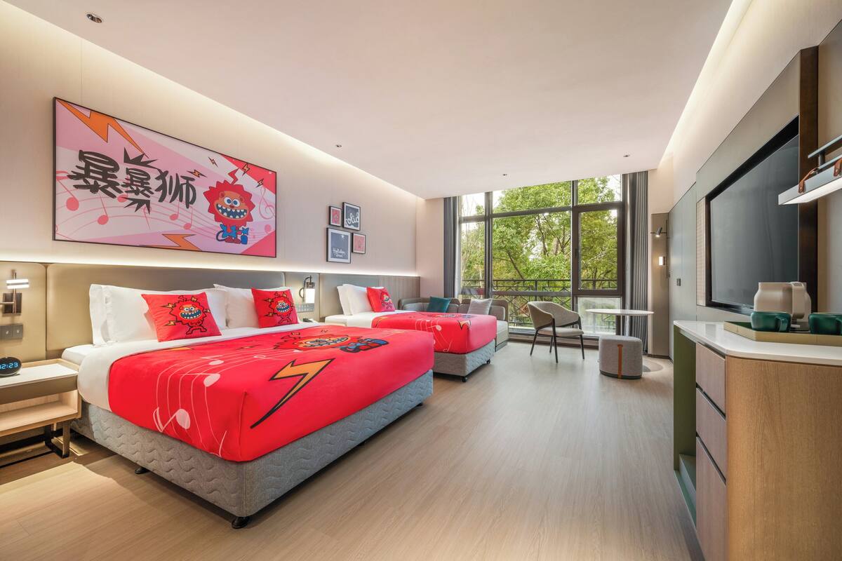 A modern hotel room with two beds, a large window, a TV, and a small kitchenette.