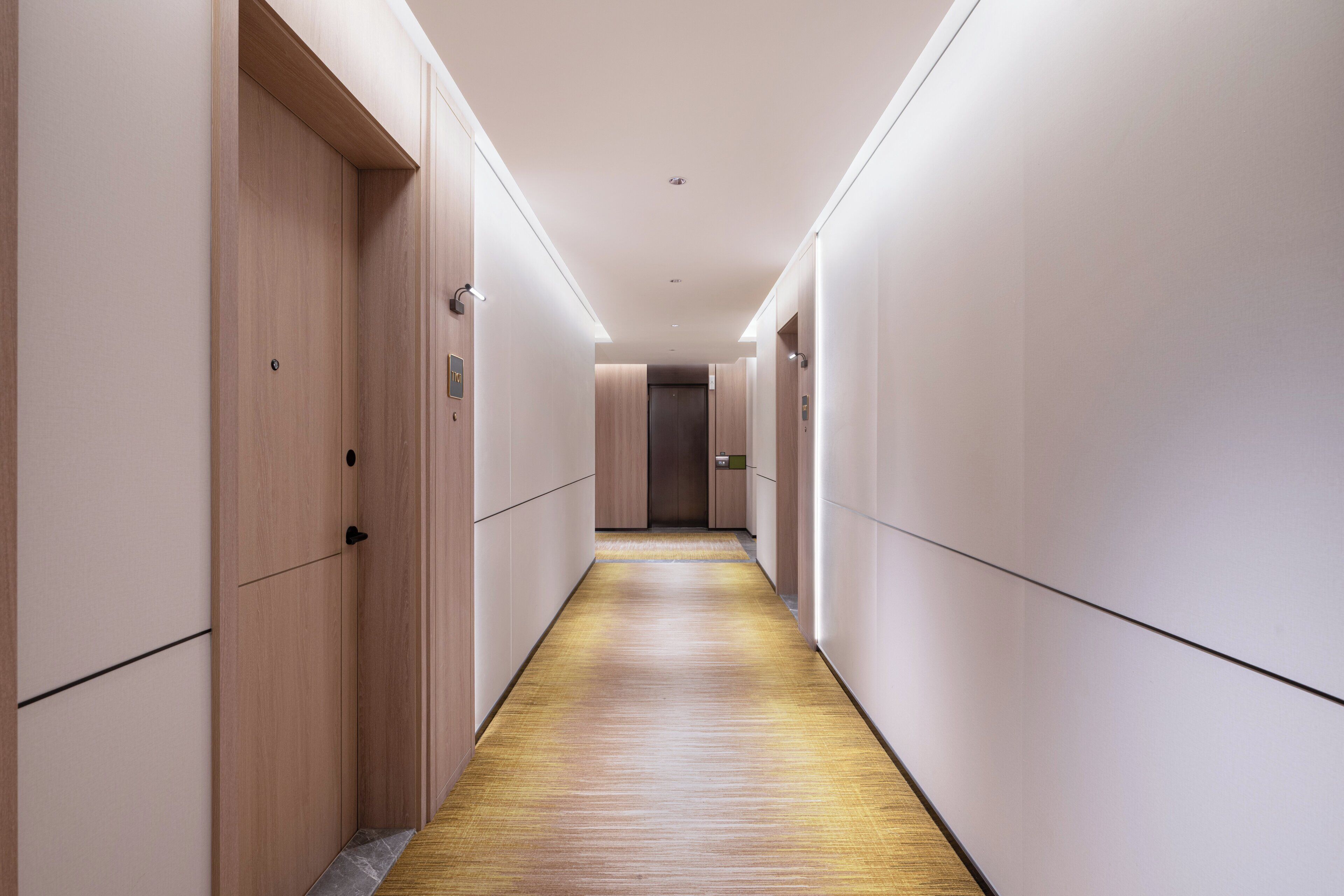A modern hotel corridor with wooden paneling on the walls and a wooden floor.