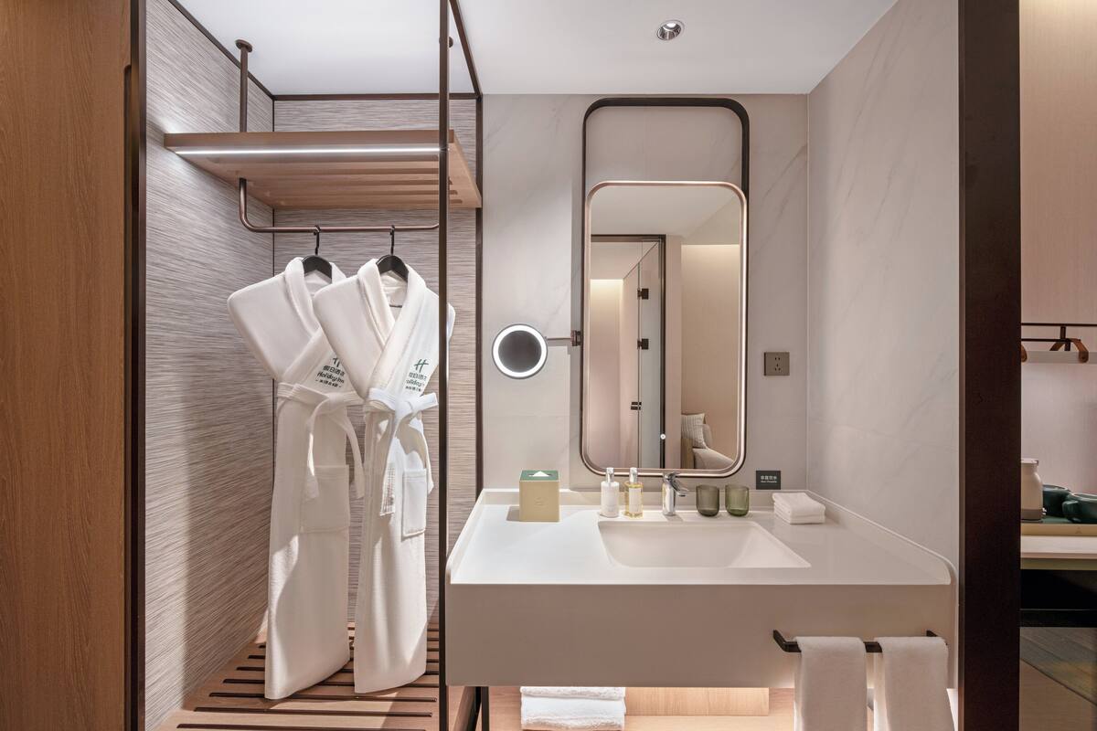A modern bathroom with a white sink, mirror, and towel rack.