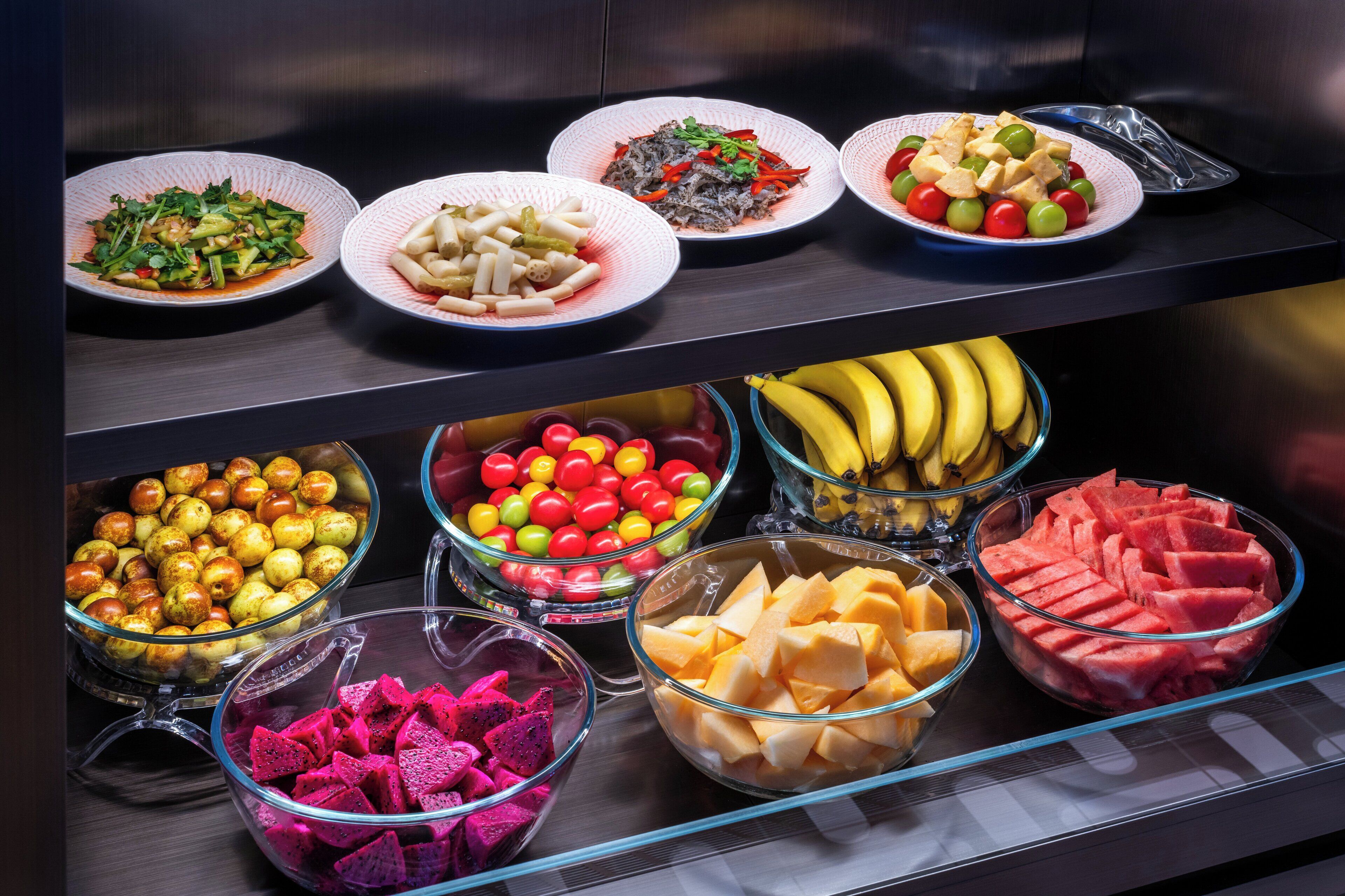 En buffet med et udvalg af retter, herunder frugt, grøntsager og salater.