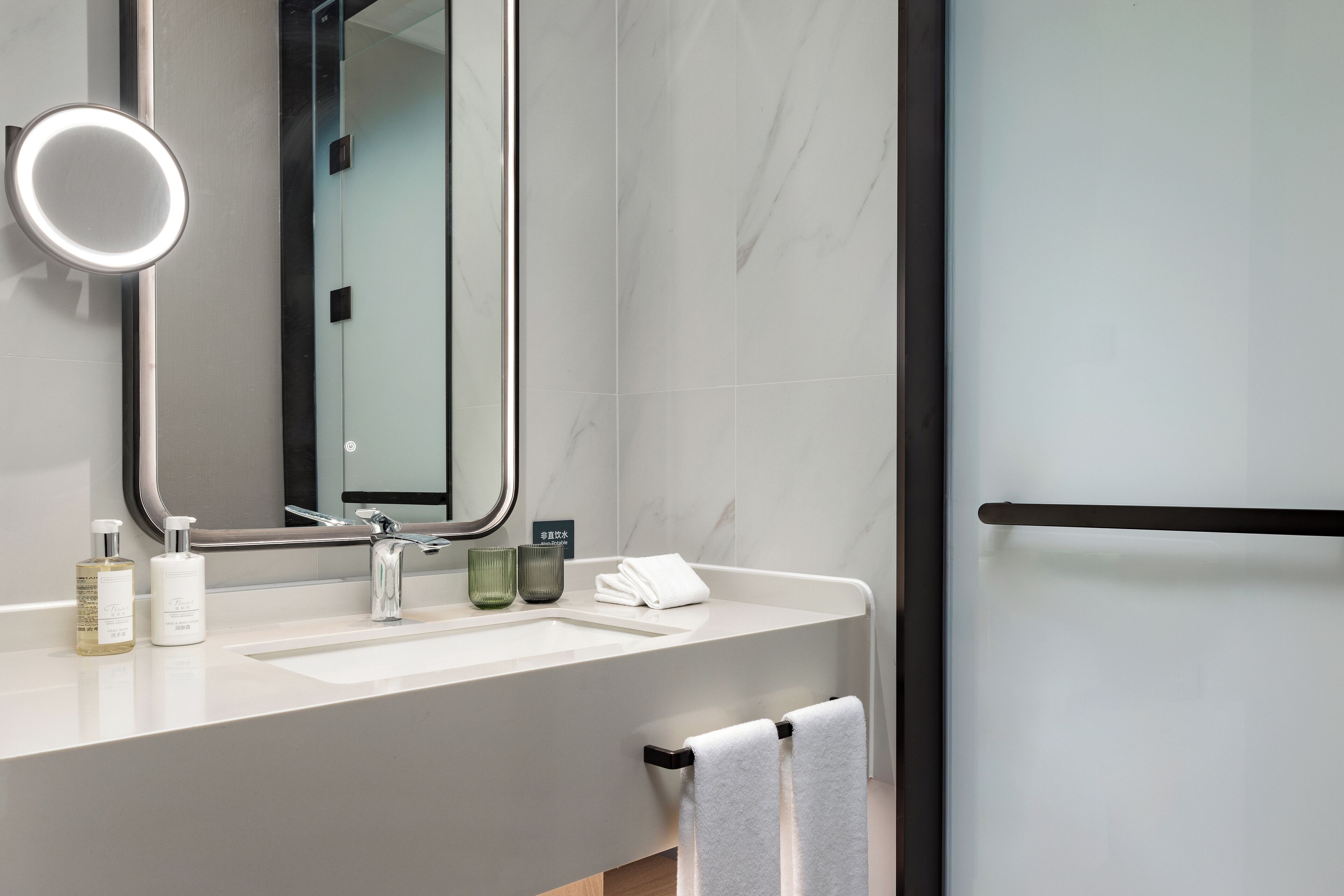 A modern bathroom with a large mirror, a sink, and a towel rack.