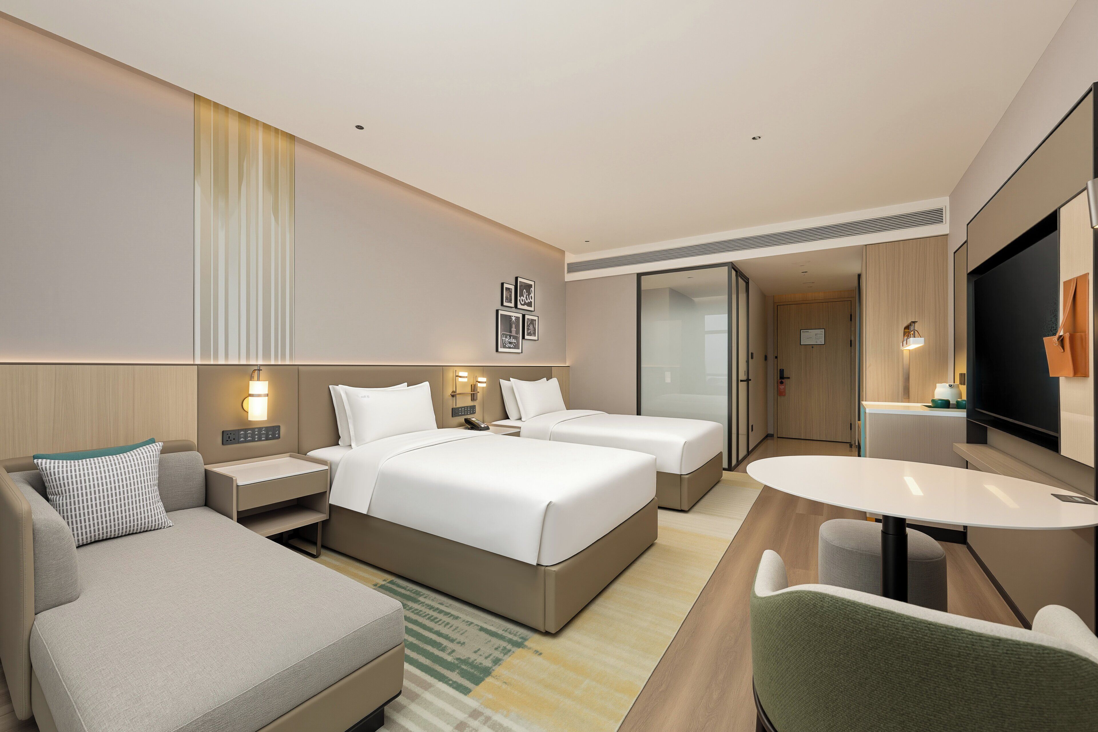 A hotel room with two beds, a sofa, a dining table, and a TV.