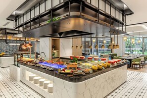 Eine moderne Küche mit Marmorarbeitsplatte, ein Buffet mit verschiedenen Speisen und eine erhöhte Ebene mit Sitzgelegenheiten.