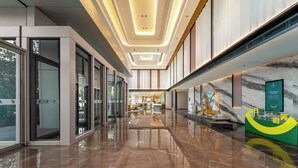 Un vestíbul d'hotel modern amb un sòl de marbre brillant, grans finestres i una recepció.