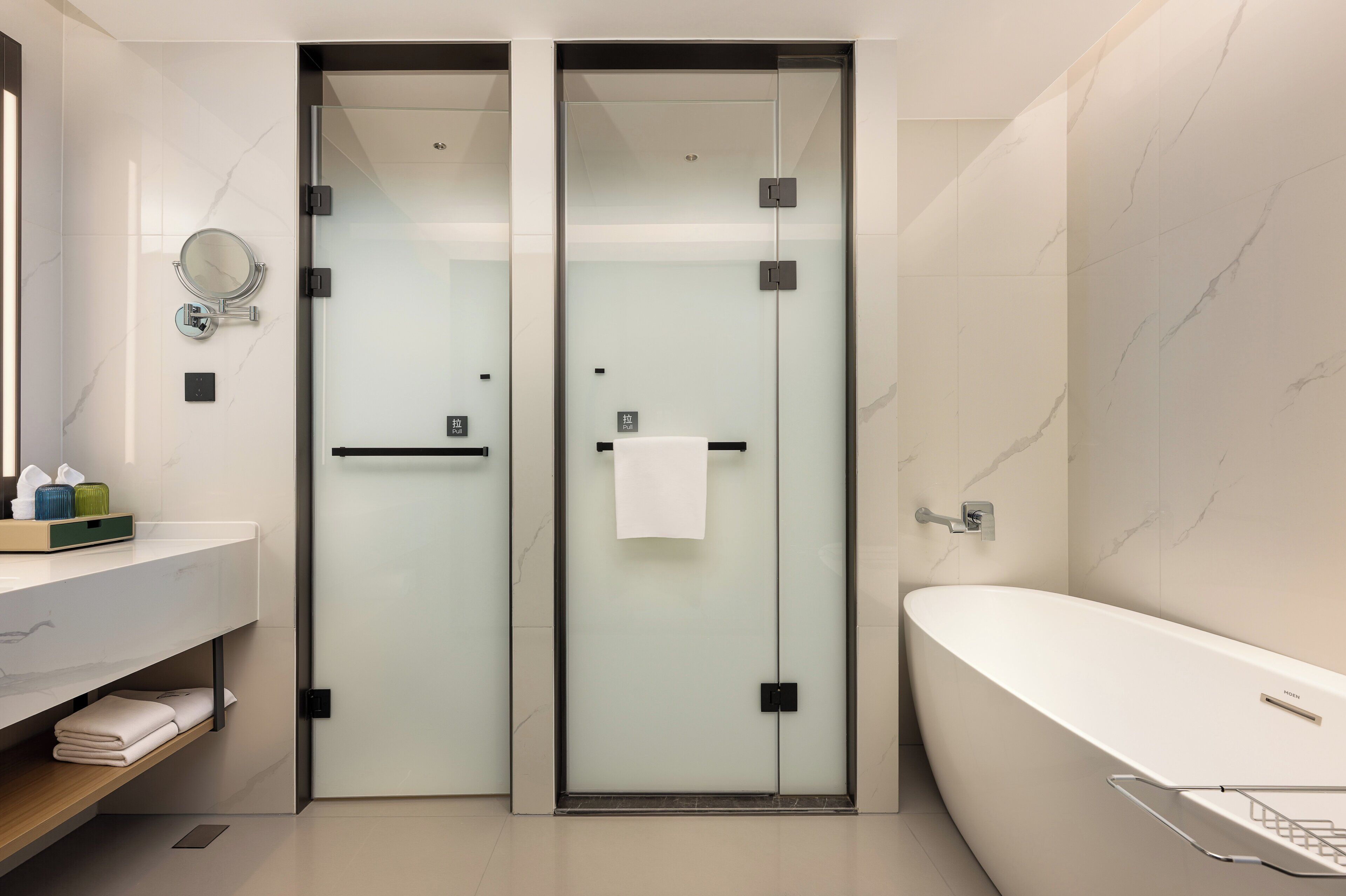 A modern bathroom with a glass-enclosed shower, a white bathtub, and a vanity with a mirror and towel rack.