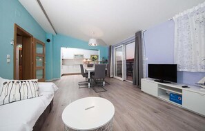 A modern living room with a sofa, a round coffee table, a TV, and a kitchen in the background. - Nice apartment in Makarska with house sea view (Makarska)