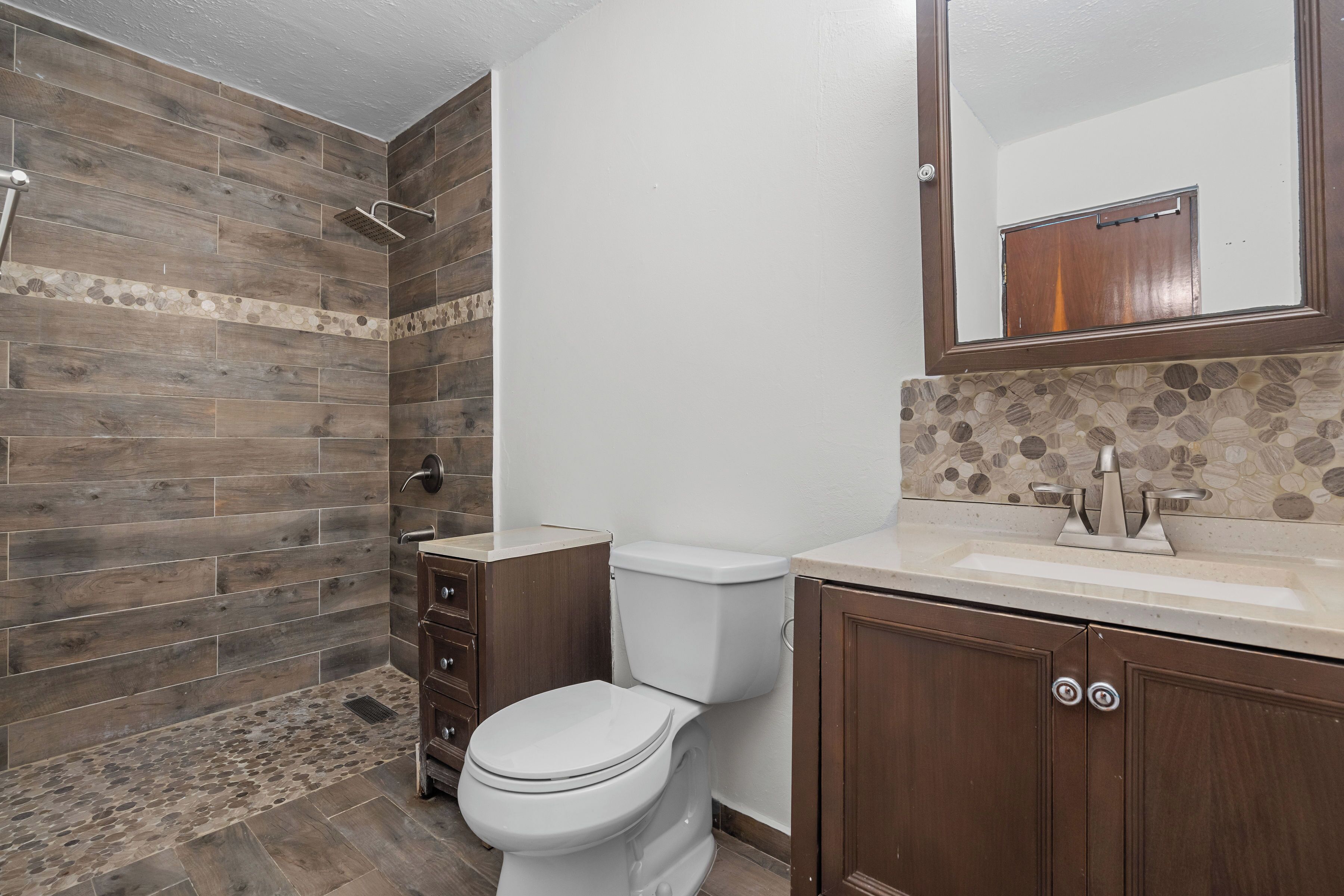 A bathroom with a shower, toilet, and vanity.