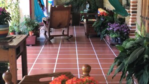 Eine Terrassenfläche mit Fliesenboden, Holzmöbeln und verschiedenen Kübelpflanzen.
