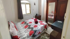 Un dormitorio con una cama, un aparador, un espejo y una ventana con cortinas.