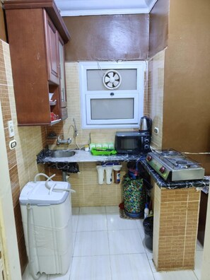 A compact kitchen with a microwave, stove, sink, and a small cabinet. - Marvelous 2-bedroom apartment with AC in Red Sea Governorate (Red Sea Governorate)