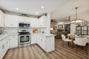 A modern kitchen with white cabinets, stainless steel appliances, and a wooden floor. - Desert Haven - Relax living, Pool, Tennis, Gated Community (Scottsdale)