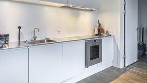 A modern kitchen with a stainless steel sink, a built-in oven, and a countertop with a kettle and a coffee maker. - Lübker Golf og Spa Resort (Nimtofte)