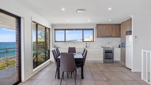 A modern kitchen with a dining area, large windows, and a view of the sea. - Casa al mare - Ocean View Suite (Ulladulla)