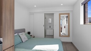 Een slaapkamer met een bed, nachtkastje en spiegel.