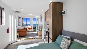 Een modern appartement met balkon, keuken en woonruimte met een bank en een eettafel.