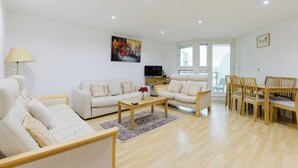 Ein modernes Wohnzimmer mit einer Couch, einem Couchtisch und einem Essbereich mit Stühlen.