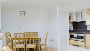 Eine moderne Küche mit Einbauofen und Essbereich mit Holztischen und einer Holztischplatte.