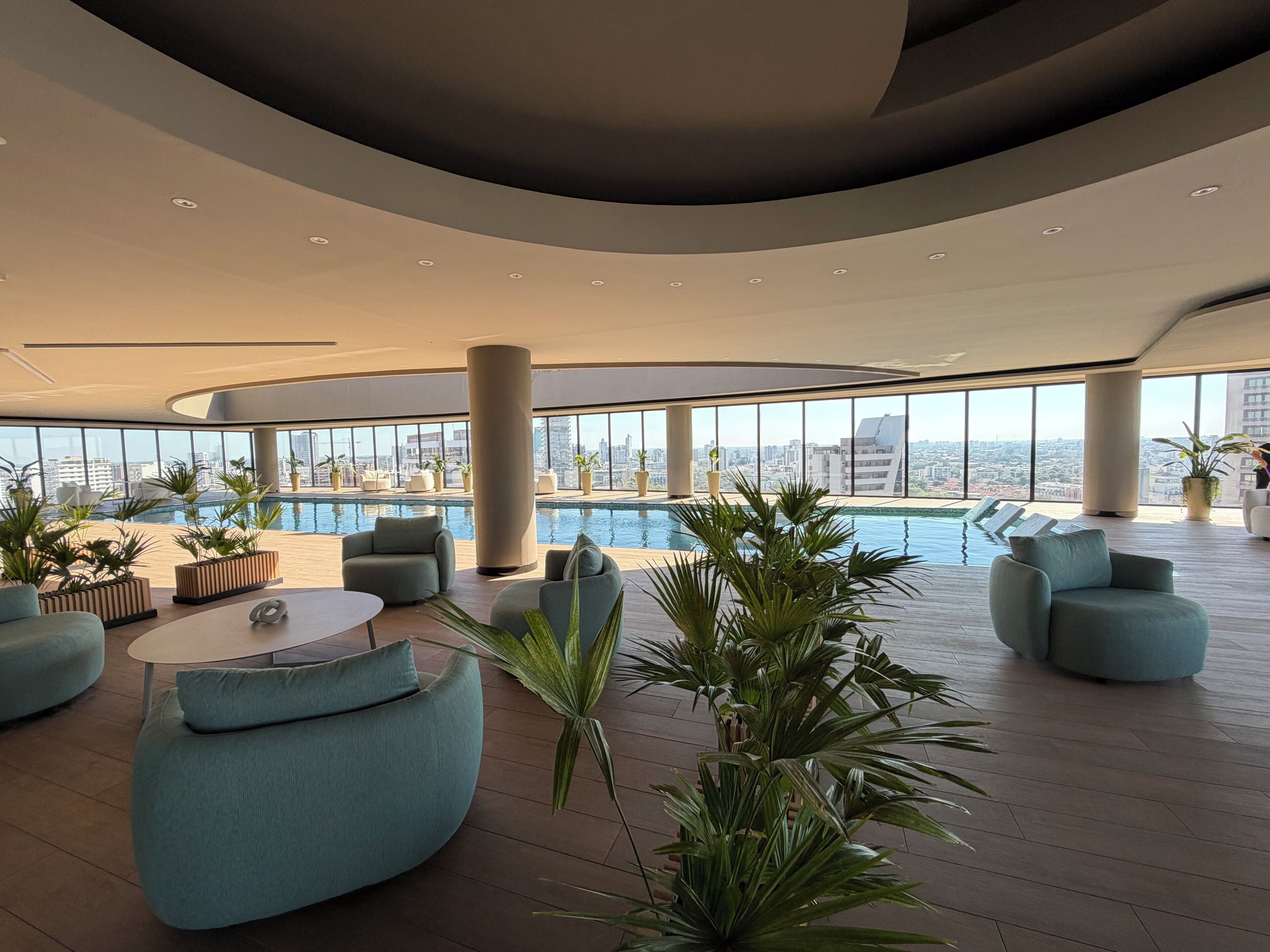 Ein stilvoller Lounge-Bereich mit Pool, Sitzgelegenheiten und großen Fenstern mit Blick auf die Stadt.